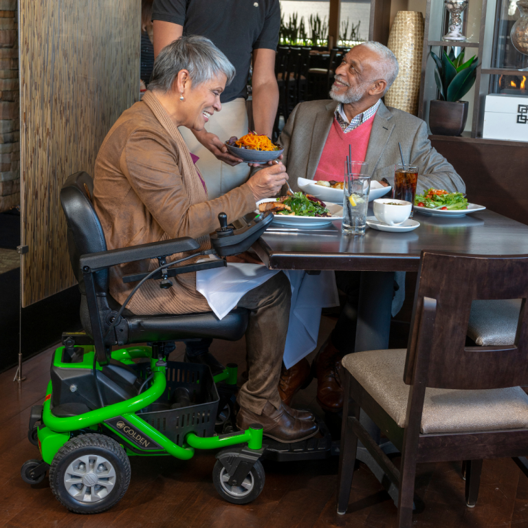 man sits at lunch next to woman in power wheelchair covered by BCBS of Arizona