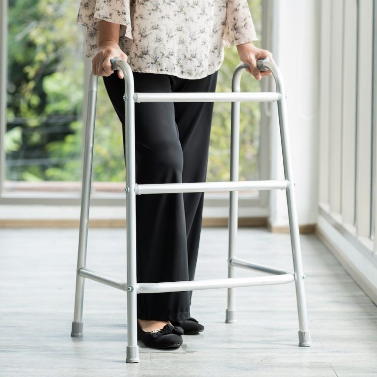 elderly woman pushes walker in her living room